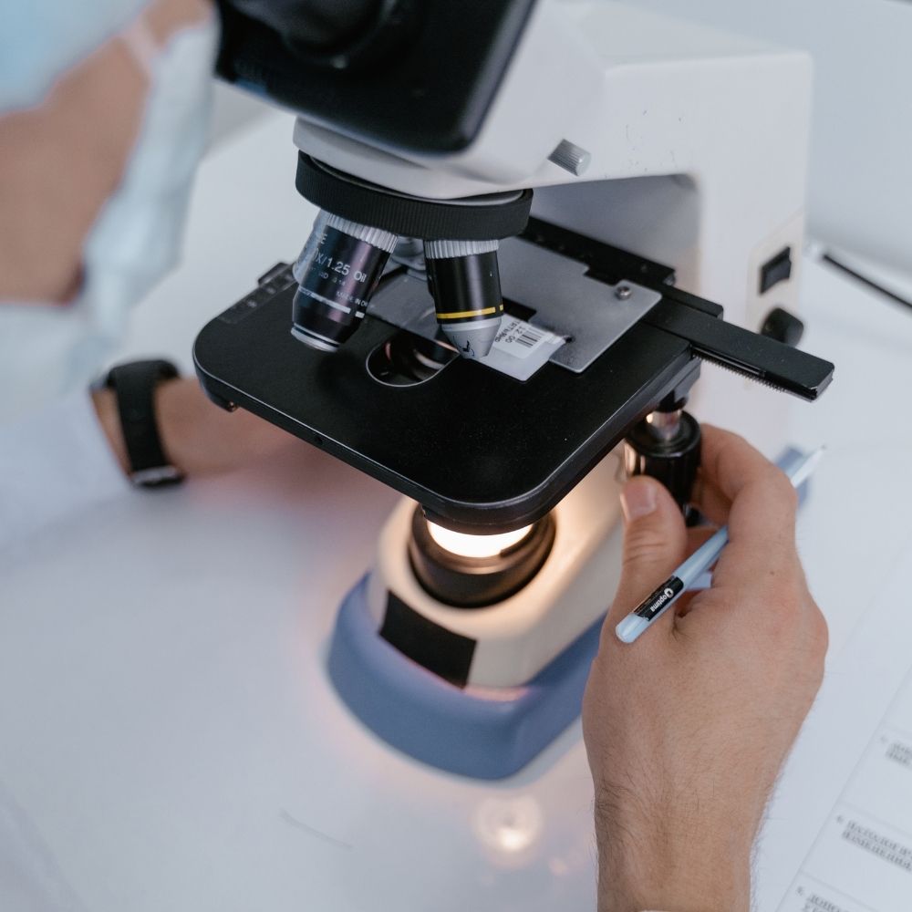Técnico ajustando un microscopio óptico en laboratorio clínico